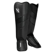 Pair of black shin guards with a brand logo on a white background