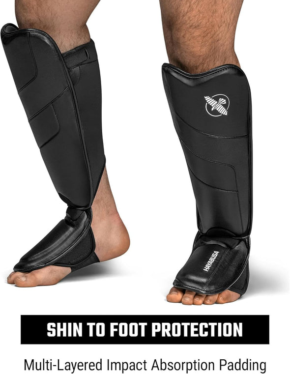 Black shin guards with impact absorption padding on a white background