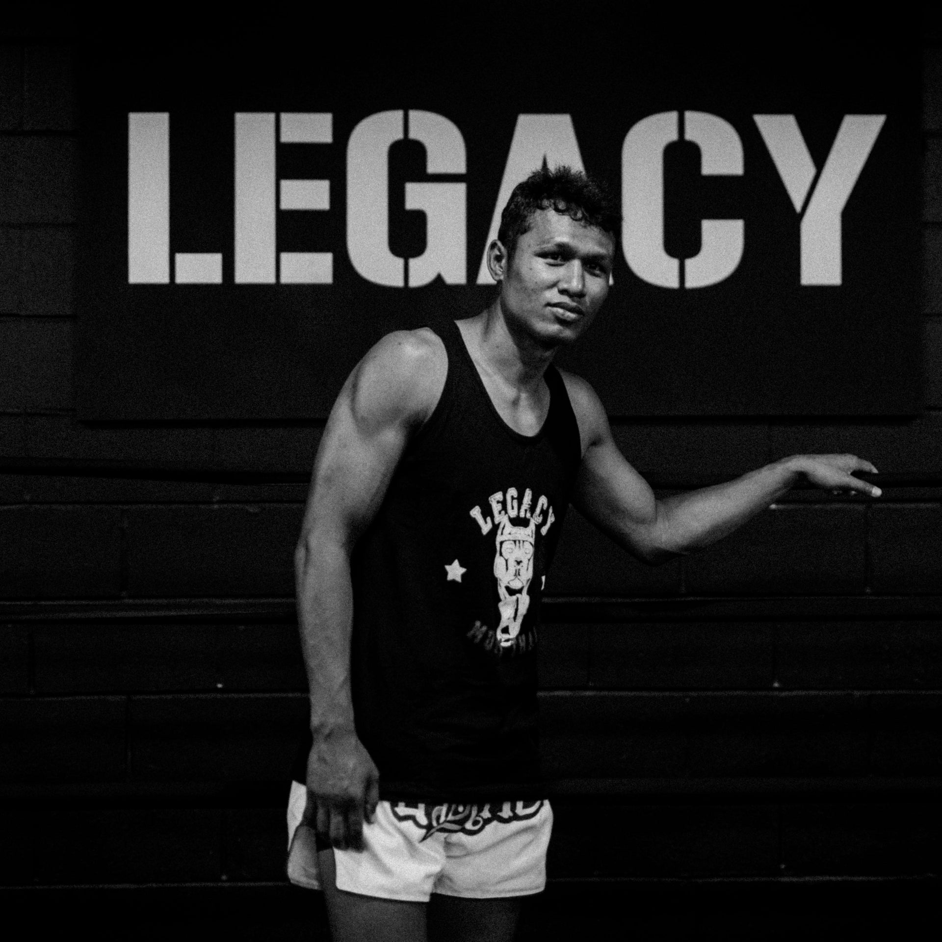 Person wearing a tank top with 'Legacy' branding in a gym setting