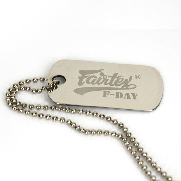 Metal dog tag with 'Fairtex F-Day' engraving on a white background