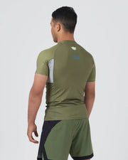 Man wearing a green athletic outfit with a logo on the back against a white background