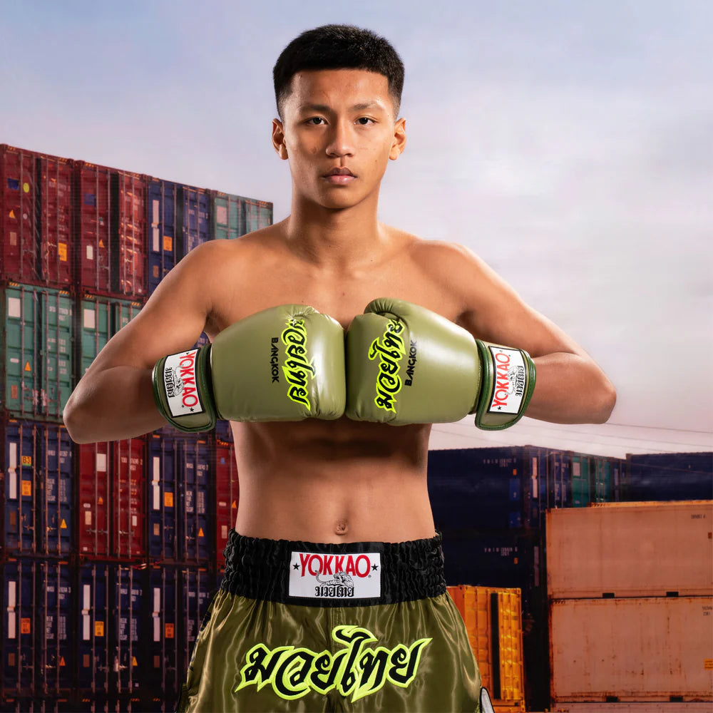 Boxer wearing green Yokkao boxing gloves and shorts in front of shipping containers.