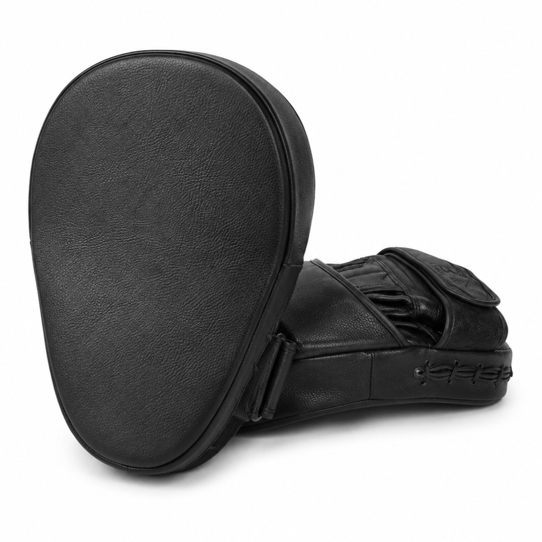 Black leather martial arts focus mitts shown from the back and side, featuring a textured leather surface and adjustable strap closure, on a white background.