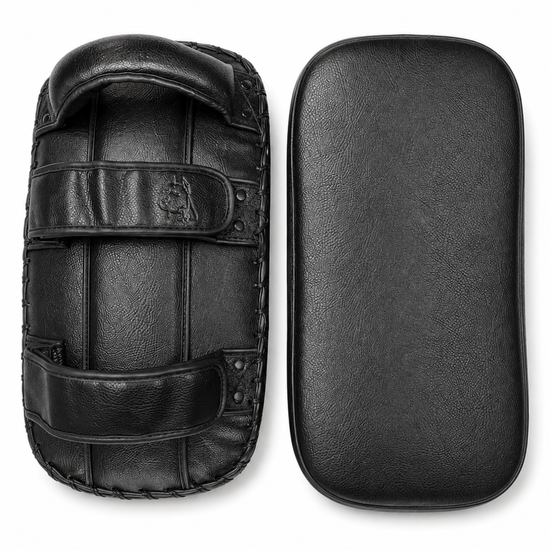 Black leather martial arts striking pads shown from two angles: one with straps and handle, and one flat rectangular pad, on a white background.