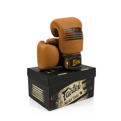 Pair of brown boxing gloves on a black Fairtex branded box against a white background