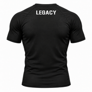 Black short-sleeve athletic shirt shown from the back, featuring the word 'LEGACY' printed in white stencil-style letters across the upper back, on a plain white background.