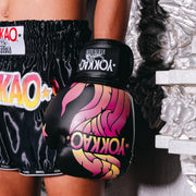 Person wearing YOKKAO branded boxing shorts and gloves in a boxing ring.