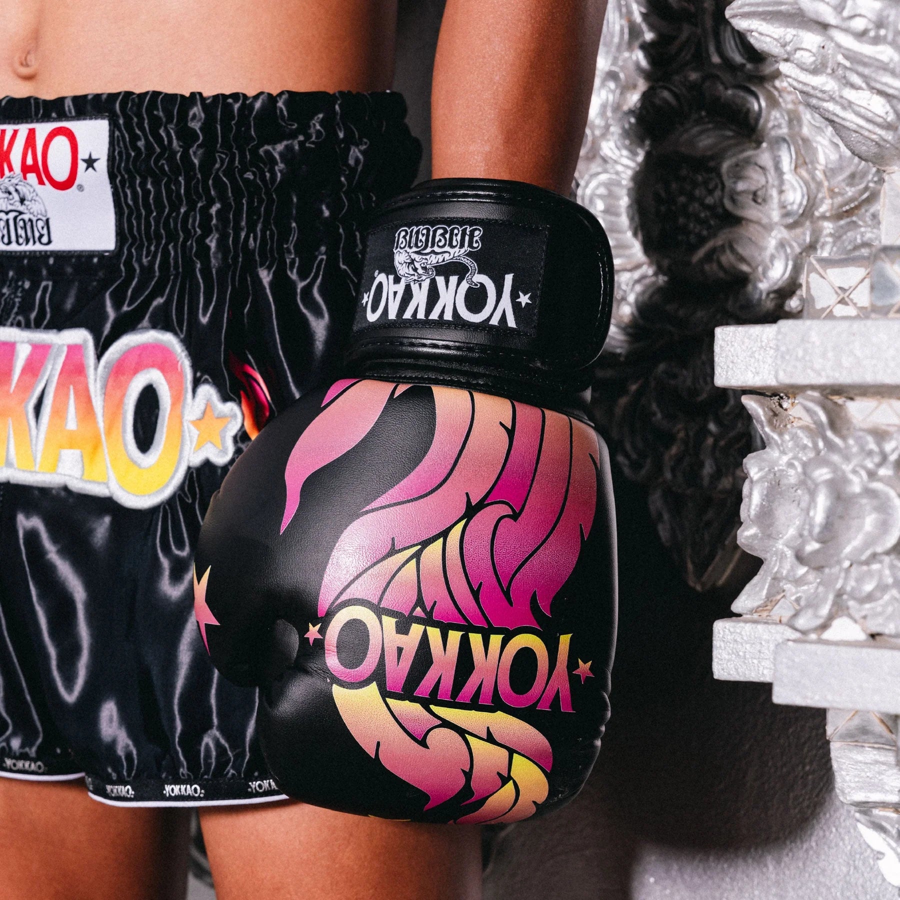 Person wearing YOKKAO branded boxing shorts and gloves in a boxing ring.