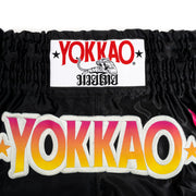 Black athletic shorts with colorful 'Yokkao' branding on a white background