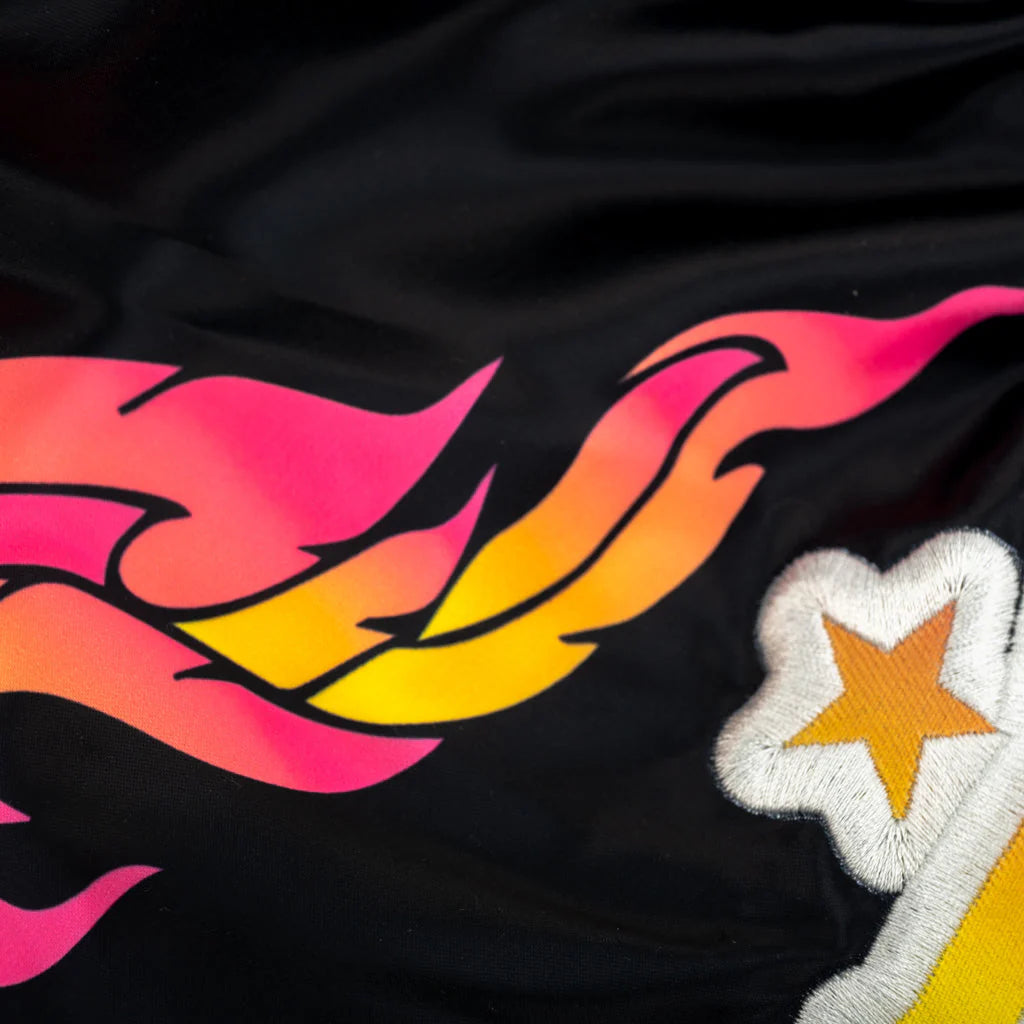 Black fabric with pink, orange, and yellow flames and a white star with a yellow center.