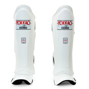 Pair of white shin guards with Yokkao branding on a white background
