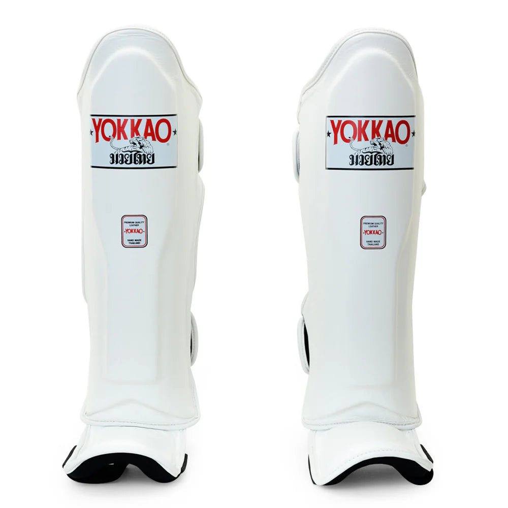Pair of white shin guards with Yokkao branding on a white background