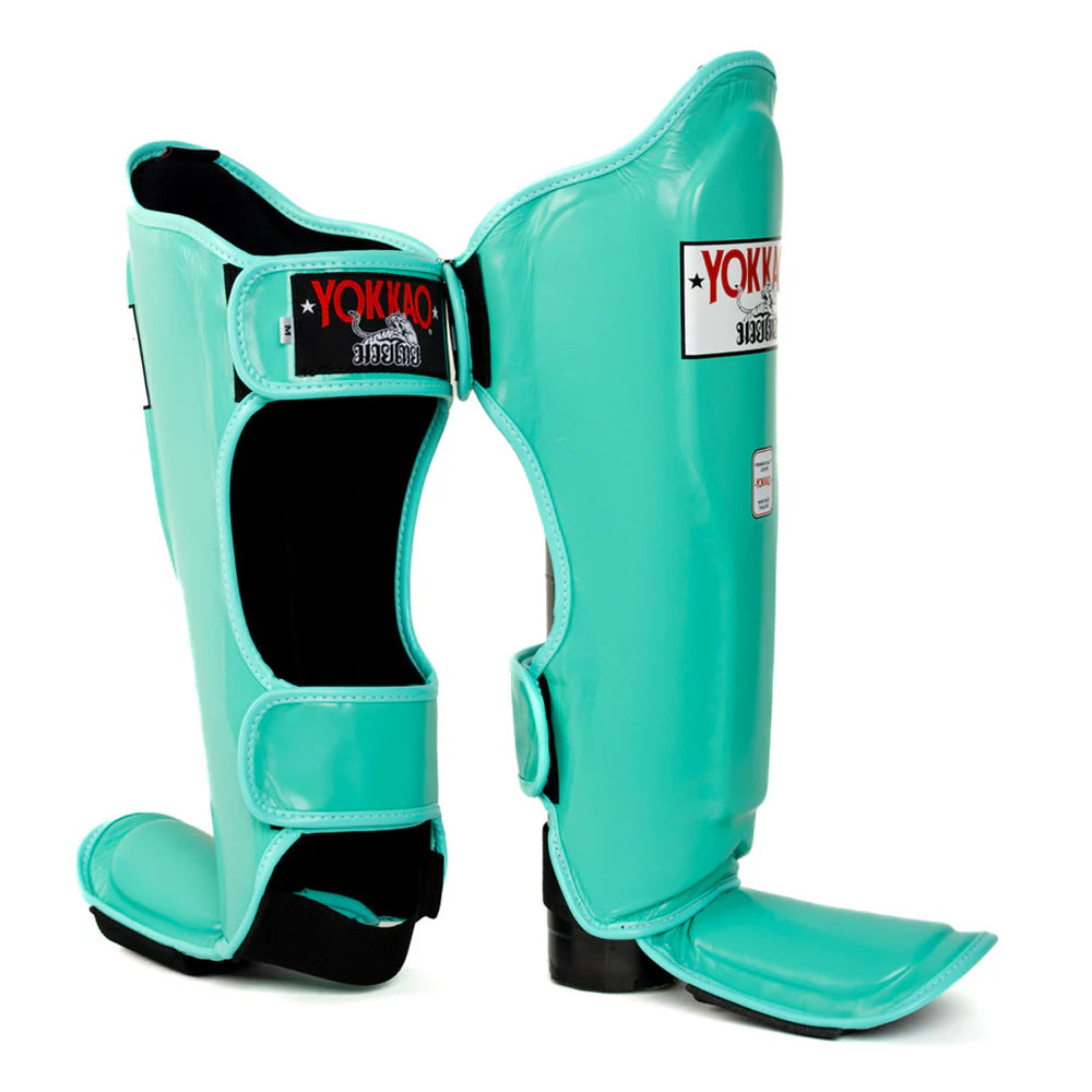 Turquoise shin guards with black accents on a white background, featuring YOKKAO branding.