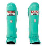 Pair of teal shin guards with Yokkao branding on a white background