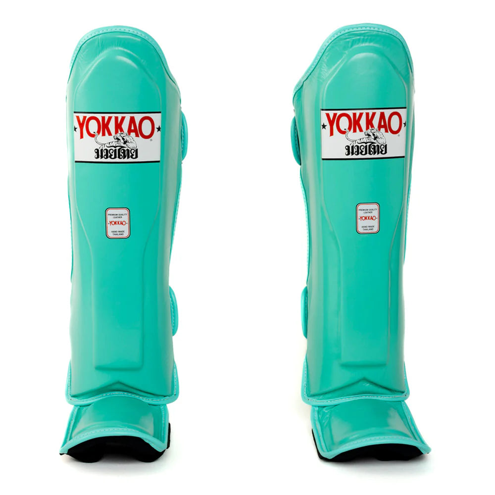 Pair of teal shin guards with Yokkao branding on a white background