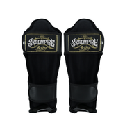 Pair of black shin guards with 'Sksempire Boxing' logo on a white background
