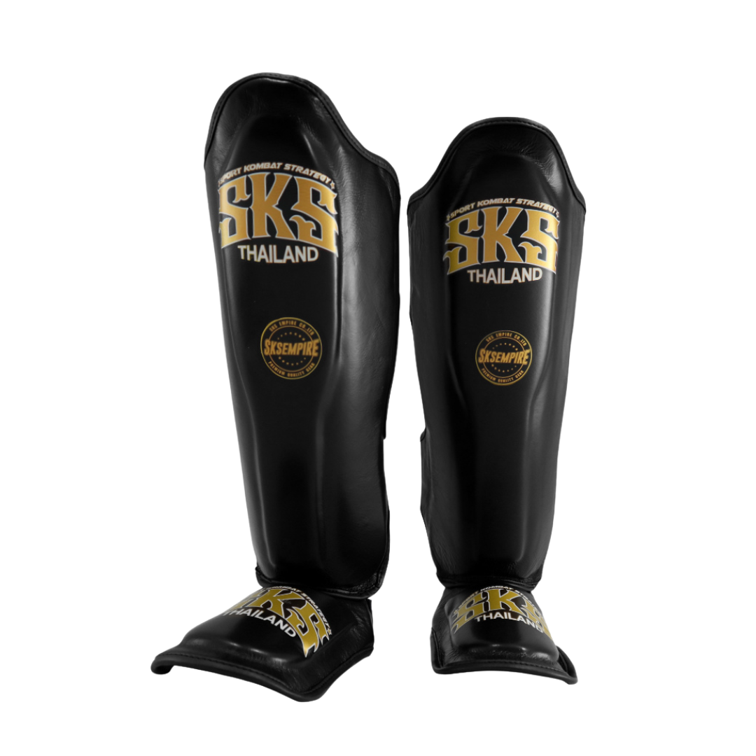 Black shin guards with gold 'SKS Thailand' branding on a white background
