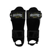 Pair of black shin guards with 'Skeempire Boxing' branding on a white background