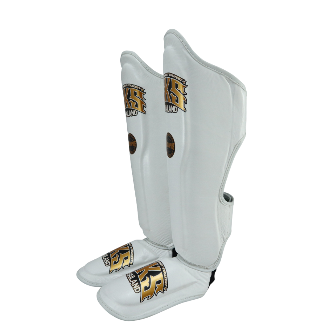 Pair of white shin guards with gold logos on a white background