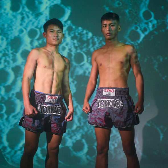 Two men wearing Yokkao boxing shorts against a textured blue background