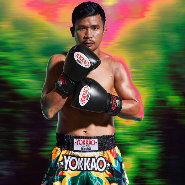 Boxer wearing Yokkao gloves and shorts against a colorful, blurred background